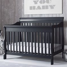 a black crib with white sheets and a dalmatian toy