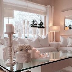 a living room filled with white furniture and lots of pillows on top of a glass table