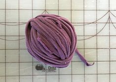 a purple ball of yarn sitting on top of a white tile floor next to a ruler