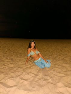 a woman sitting on top of a sandy beach next to a sky filled with stars