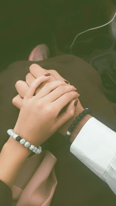 two people holding hands while sitting in the back seat of a car with their hands on each other's wrist