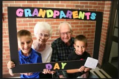 an older man and two young boys holding up a photo frame with the words grandparents day written on it