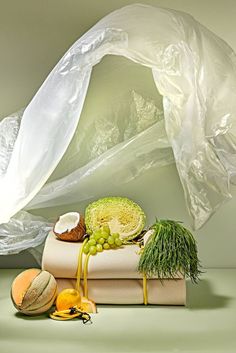 various fruits and vegetables wrapped in plastic on top of each other, including melons