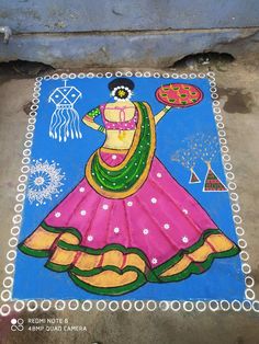 a colorful painting on the ground with a woman holding a pot and wearing a sari