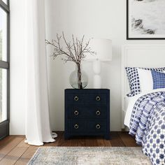 a bed room with a neatly made bed and a night stand next to a window