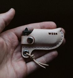 a hand holding a leather knife case with the word wern on it's side