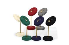 four different colored jewelry stands with gold and silver necklaces on top of each one