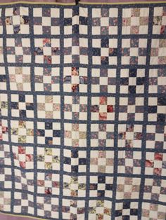 a blue and white quilt hanging on a wall