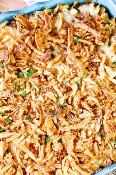 a blue casserole dish filled with pasta and meat, garnished with green onions