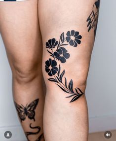 a woman's legs with tattoos on them and flowers in the lower part of her thighs