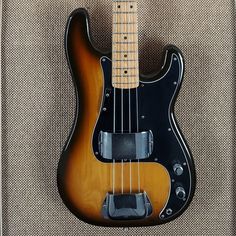 an electric bass guitar sitting on top of a carpeted floor next to a wall