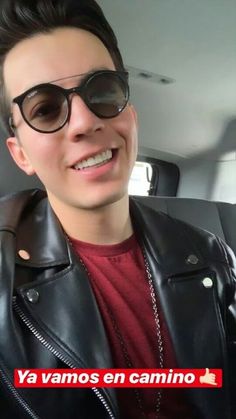 a man wearing sunglasses is smiling in the back seat of a car with another person behind him