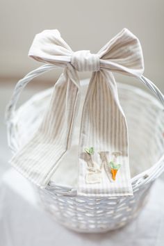 a white basket with a bow tie and two napkins in it on a table