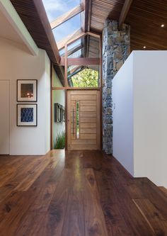 a wooden floor in front of a stone wall and door with skylight above it