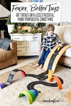 a young boy is playing with his toy car track set in the living room at christmas time