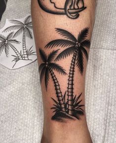 a black and white photo of a palm tree with a key tattoo on the leg