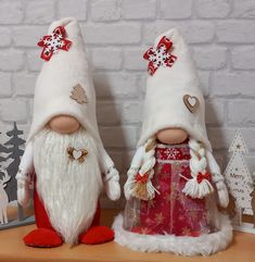 two christmas gnomes are standing next to each other on a shelf in front of a brick wall