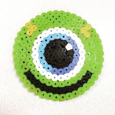 a green and black beaded object on a white surface