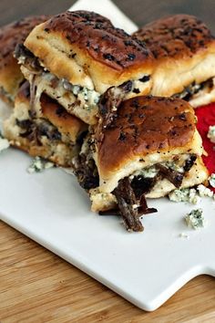 three sandwiches stacked on top of each other on a white plate with blue cheese and red sauce