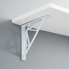 a white shelf mounted to the side of a wall with a metal bracket on it