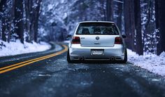 a white car driving down a snow covered road