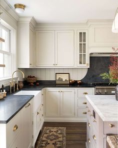 a kitchen with white cabinets, black counter tops and gold pulls on the cabinet doors