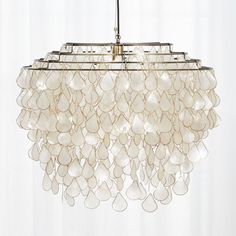 a chandelier hanging from a ceiling in a room with white walls and curtains