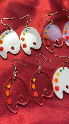 five pairs of elephant shaped earrings on a red cloth with white and orange designs in the middle