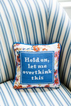 a blue and white striped chair with a pillow that says hold on, let me overthik this