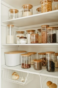 an organized pantry with lots of food in glass containers and bread rolls on the shelves