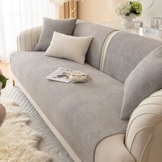 a living room with a gray couch and white furnishing on the floor in front of a window