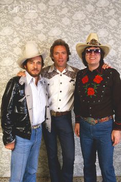 three men standing next to each other wearing cowboy hats