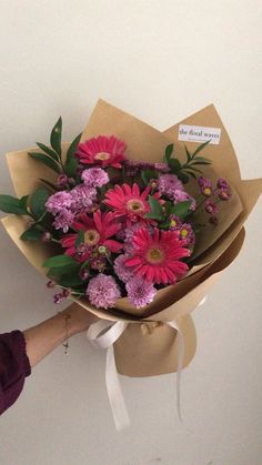 a woman holding a bouquet of pink and purple flowers