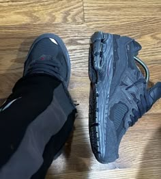 two pairs of black shoes on top of a wooden floor next to a pair of leggings