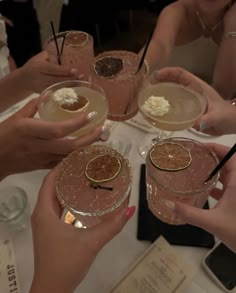 several people holding up glasses with drinks in them