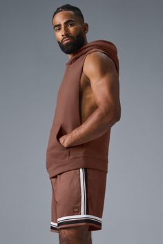 Stay cozy without sacrificing style in the Renown Sleeveless Hoodie. It has deep armholes, a kangaroo pocket, and a laid-back cut. And wait till you feel the Alo signature Renown fabric—it's smooth on the outside, a little fleecy on the side, and heavyweight for a just-right drape. Add shorts and you’re covered from the gym to the street. Alo Yoga Athleisure Streetwear Tops, Alo Yoga Athleisure Tops For Streetwear, Athleisure Hoodie With Pockets For Workout, Athleisure Tops With Pockets For Streetwear, Workout Tops With Pockets For Fall, Brown Relaxed Fit Hoodie Top, Sporty Brown Hoodie For Loungewear, Sporty Vest Top For Fall, Brown Sleeveless Athleisure Activewear