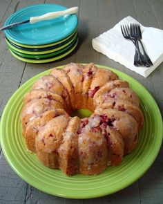 a bundt cake sitting on top of a green plate next to plates with forks