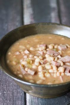 a bowl filled with ham and bean soup on top of a wooden table