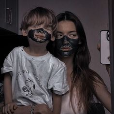 a woman and child with black face paint on their faces in front of a mirror