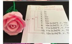 a crocheted rose sitting on top of a piece of paper next to a calculator