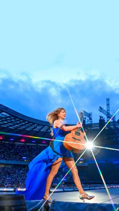 a woman in a blue dress is holding an acoustic guitar and performing on stage at a concert