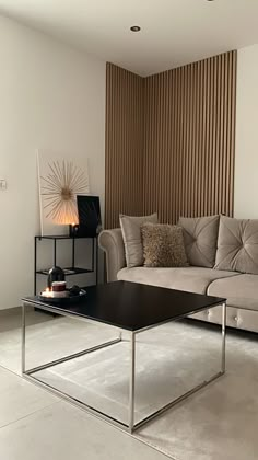 a living room with a couch, coffee table and lamp in the corner next to it