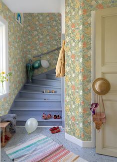 a room that has some stairs and colorful wallpaper on the walls with shoes in it