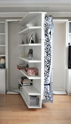 a white book shelf filled with books next to a door and shelves on the wall