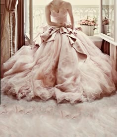 a woman in a ball gown sitting on a window sill looking out the window