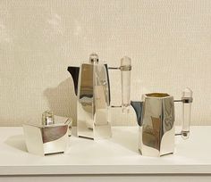 three silver vases sitting on top of a white table