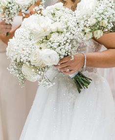 two bridesmaids holding bouquets of white roses and baby's breath in their hands