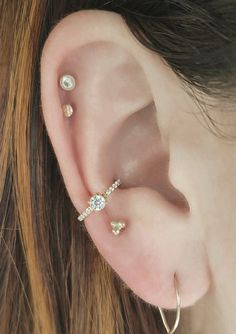 a woman wearing three different types of ear piercings