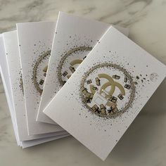 three cards with gold and black designs on them sitting next to each other in front of a marble surface