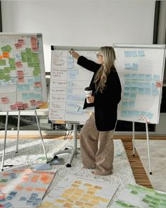 a woman standing in front of a whiteboard with sticky notes on it